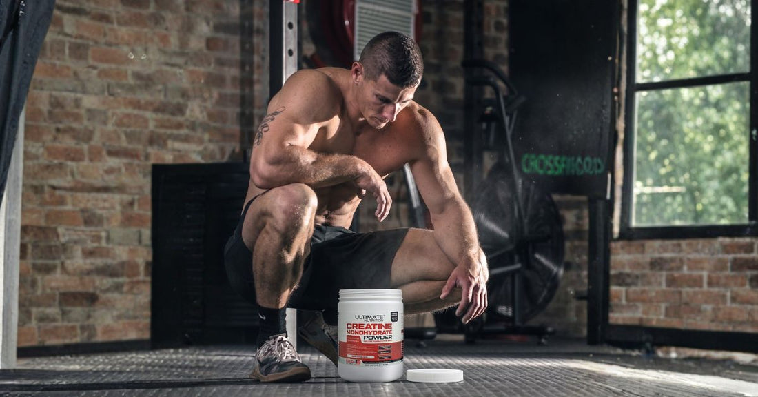 ultimate nutrition creatine monohydrate powder container in a gym setting with a muscular athlete kneeling on the floor