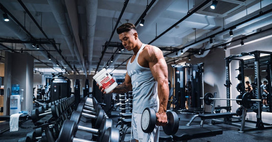 person holding a dumbbell and ultimate nutrition creatine monohydrate in a gym to illustrate what to look for and avoid in pre workout supplements for the article pre workout supplements what to look for and what to avoid