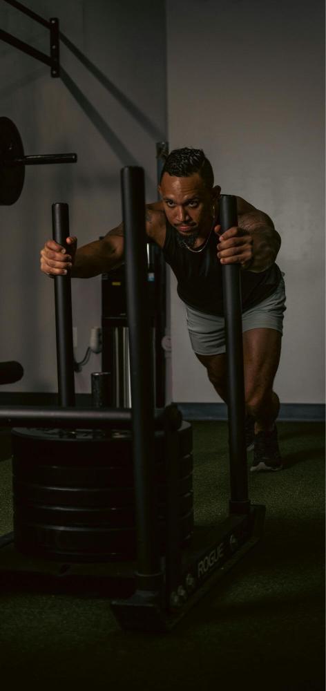 Strength athlete pushing a heavy sled in the gym, illustrating performance and endurance benefits linked to collagen support.
