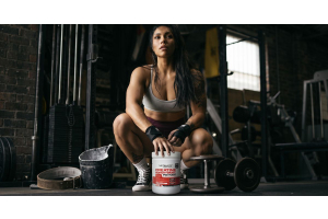 athlete in a gym crouching beside ultimate nutrition creatine monohydrate powder to illustrate how creatine supports post workout recovery during the 30 minute window for the article post workout recovery the 30 minute window explained