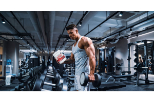 person holding a dumbbell and ultimate nutrition creatine monohydrate in a gym to illustrate what to look for and avoid in pre workout supplements for the article pre workout supplements what to look for and what to avoid