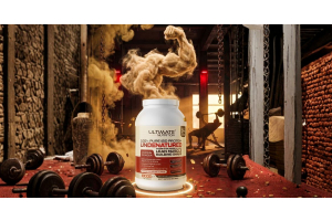 Container of Ultimate Nutrition 100 Percent Pure ISO Protein placed on a gym floor with weights in the background and a dramatic cloud of powder rising from the open container while a person lifts weights on a bench behind it